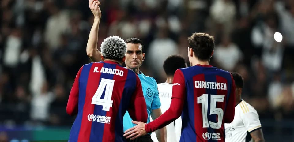 Árbitro mostrando tarjeta amarilla a jugador de Barça