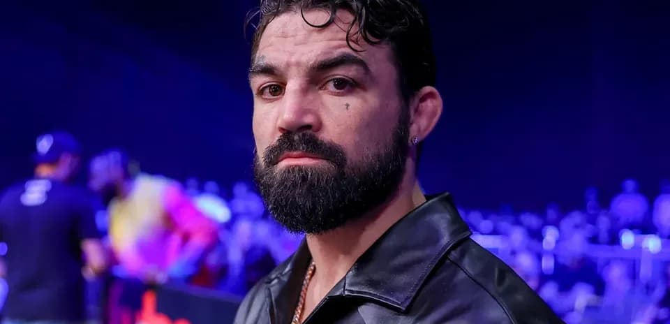 Hombre con barba en evento deportivo con público detrás