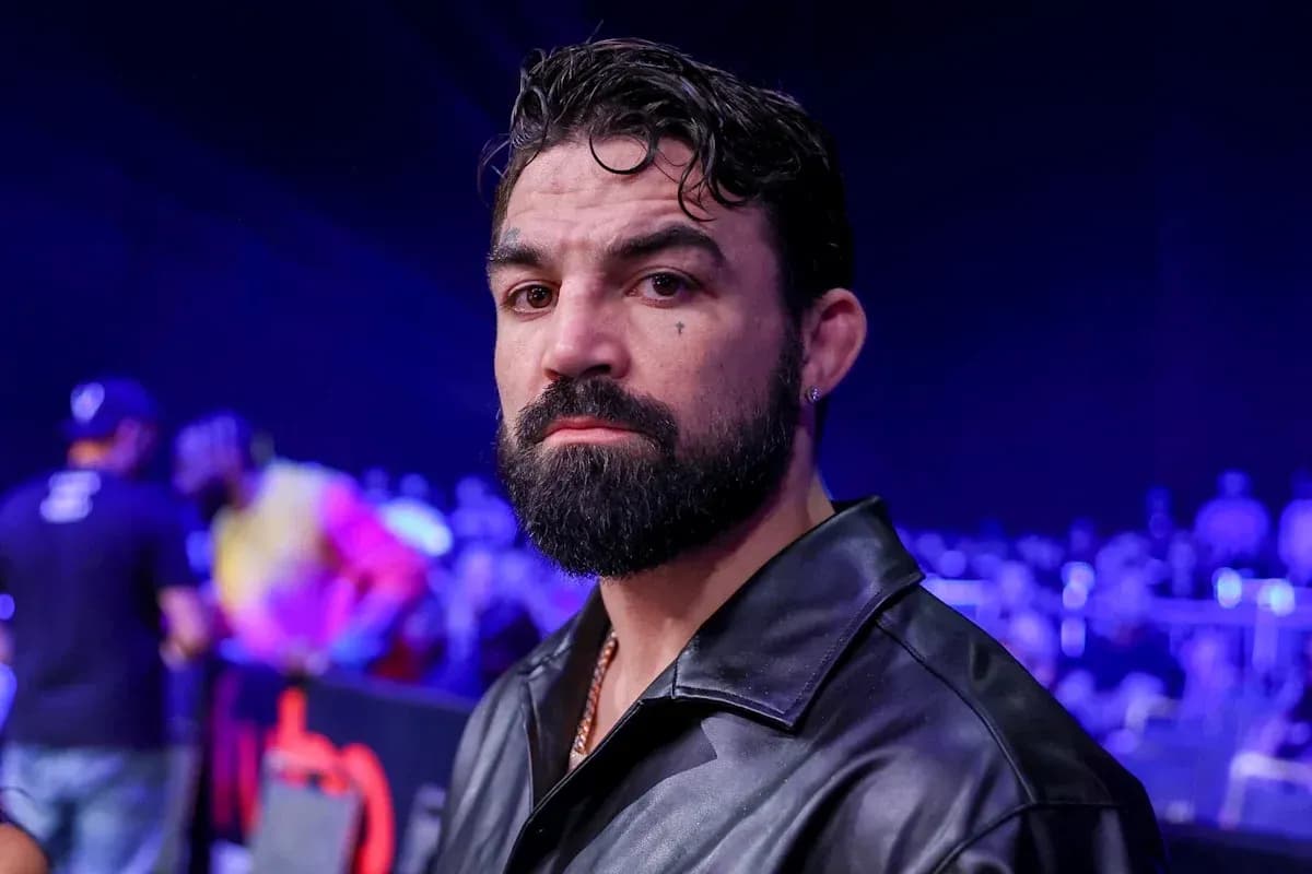 Hombre con barba en evento deportivo con público detrás