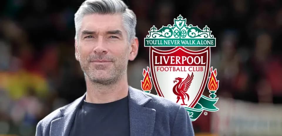Hombre sonriendo con el logo del Liverpool FC detrás