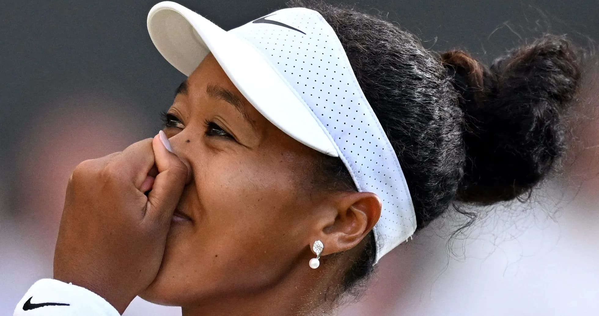 Naomi Osaka con gorra, tocándose la cara