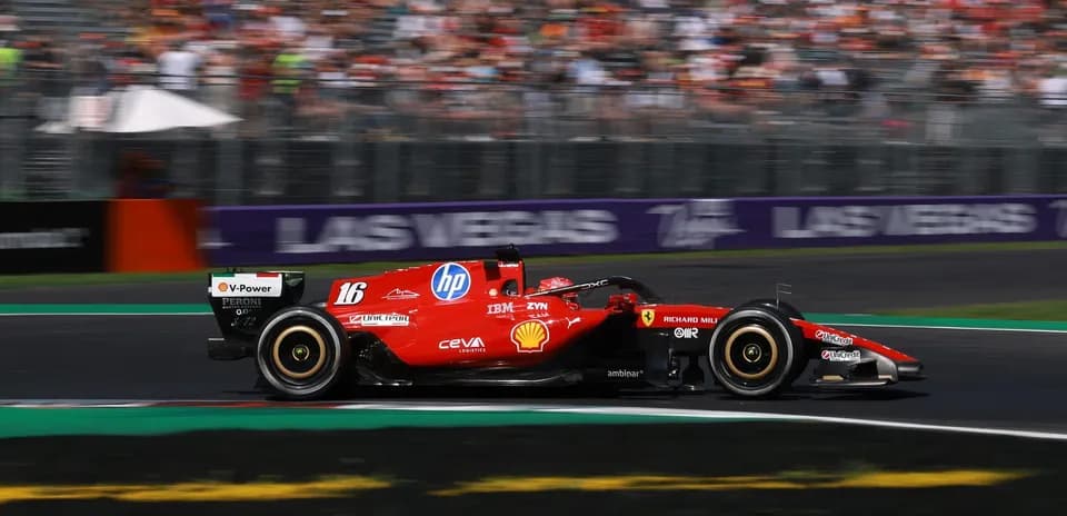 Ferrari F1 car racing on track with crowd in background