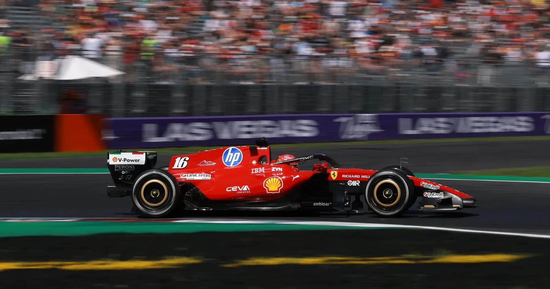 Ferrari F1 car racing on track with crowd in background