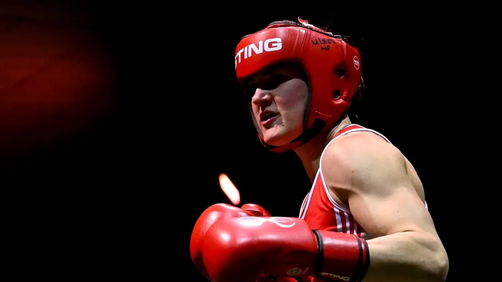 Boxeadora en acción con guantes rojos y casco