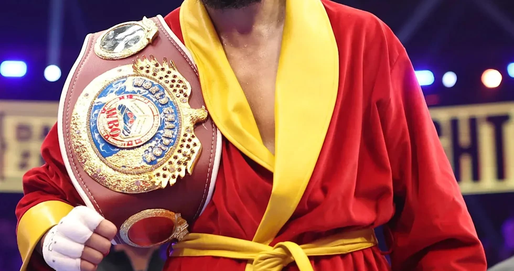 Boxeador con cinturón en bata roja y amarilla