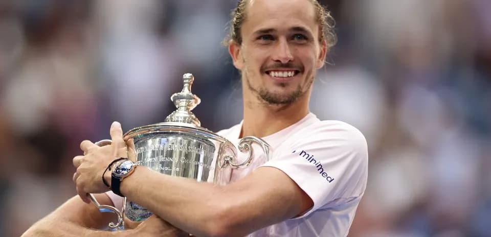 Jugador sosteniendo el trofeo de tenis sonriente