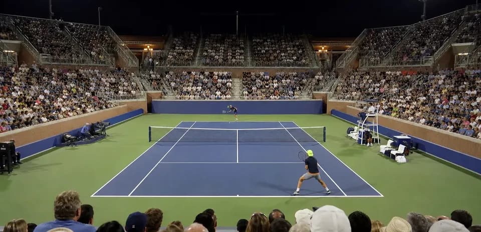 Partido de tenis bajo las luces con espectadores