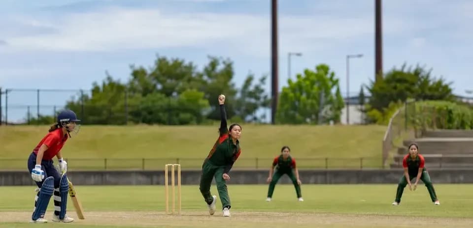 Jugadora lanzando la bola en partido de cricket