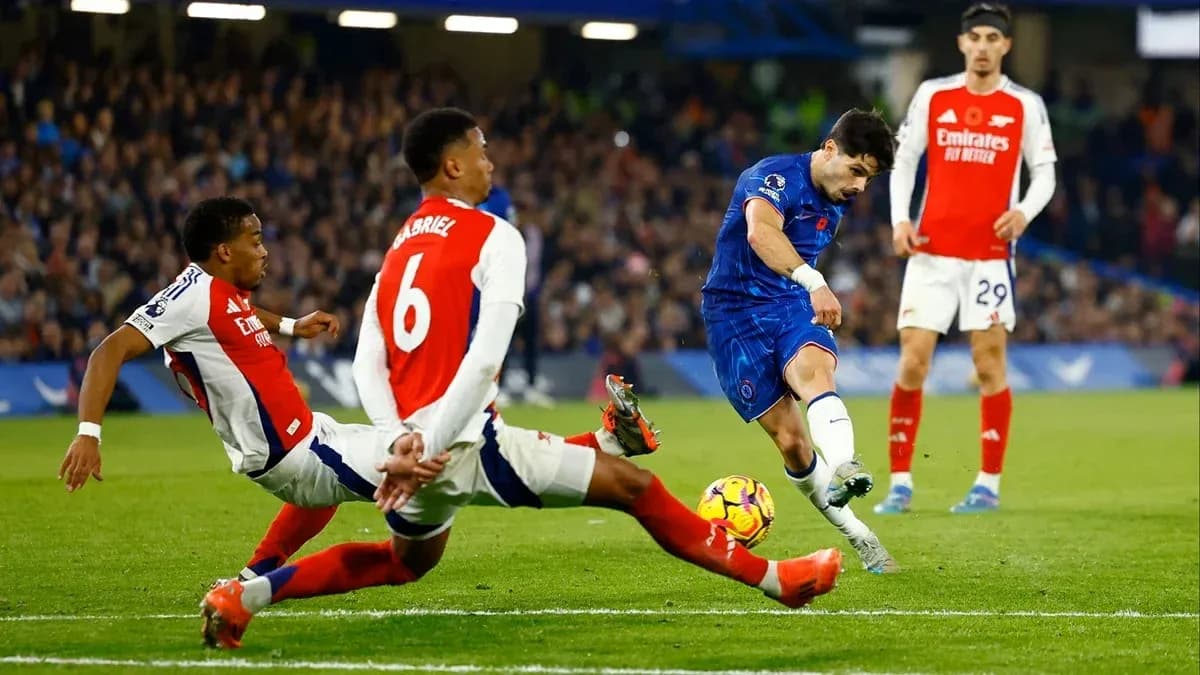 Jugador de Chelsea disparando mientras es tackleado por Arsenal