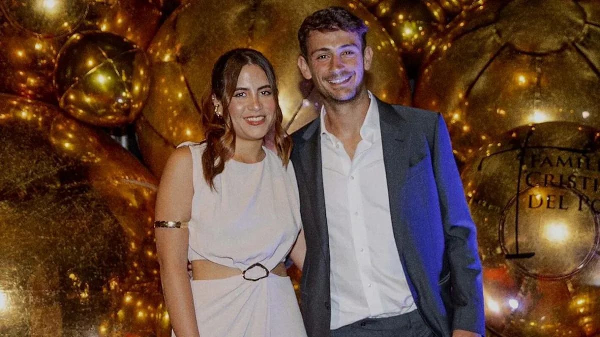 Pareja posando frente a globos dorados en evento