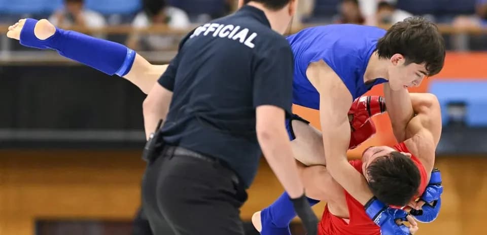 Luchador azul levantando a oponente rojo en combate