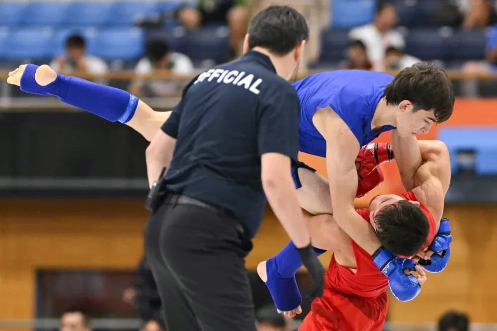 Luchador azul levantando a oponente rojo en combate