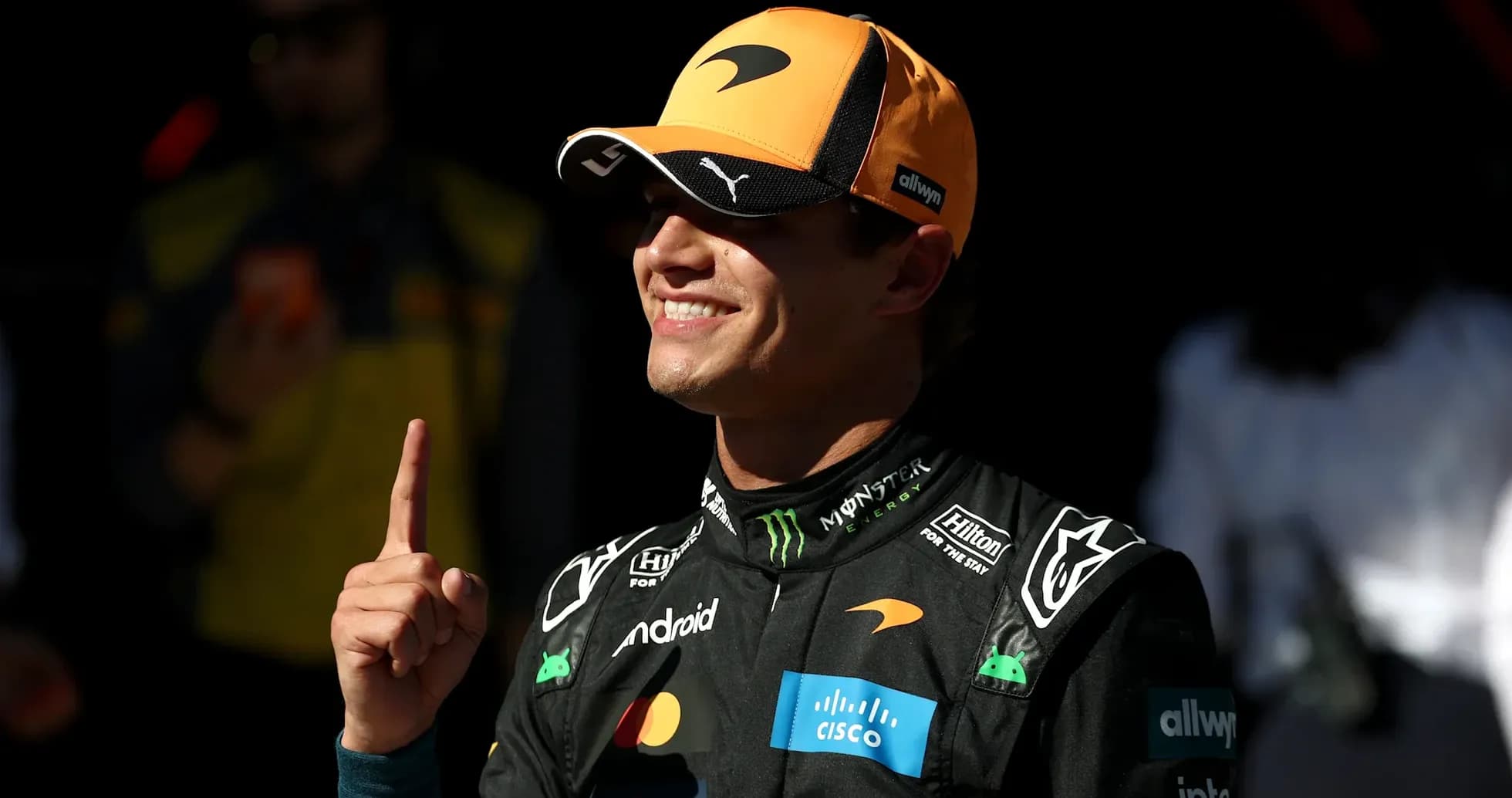 Piloto de McLaren mostrando el número uno con la mano