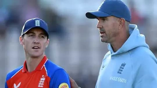 Entrenador hablando con jugador en el campo de cricket