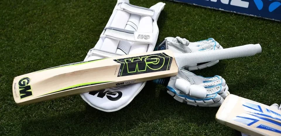 Equipo de cricket: bate, guantes y almohadilla en campo