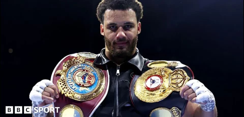 Boxeador sosteniendo cinturones de campeón en el ring