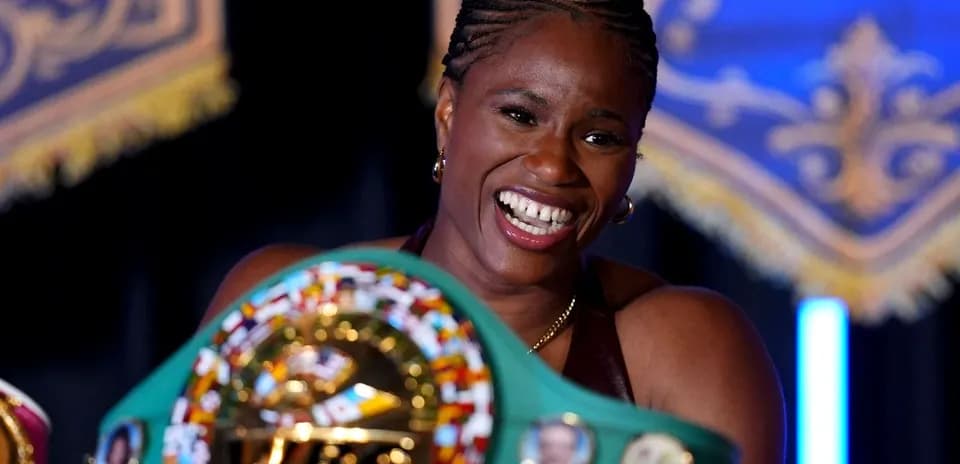 Boxeadora sosteniendo su cinturón de campeona sonriente