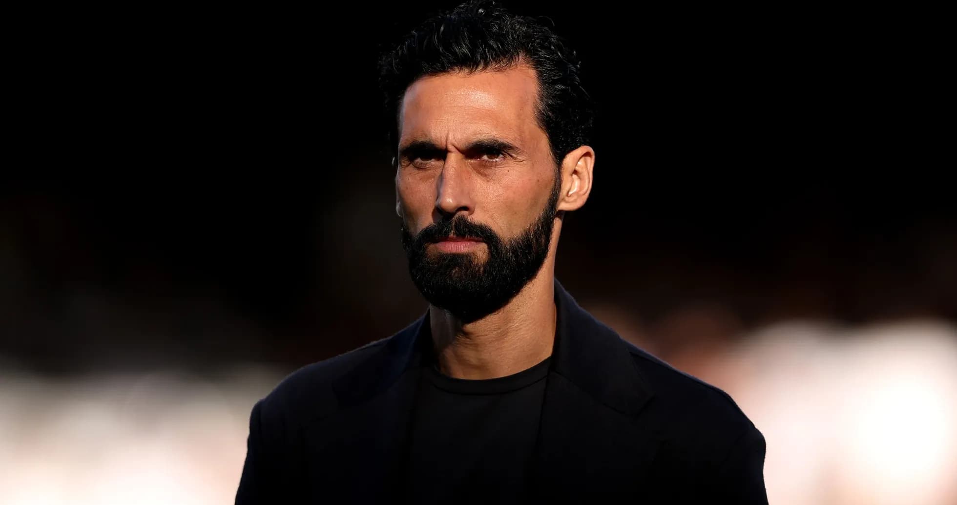 Hombre con barba y cabello oscuro mirando intensamente