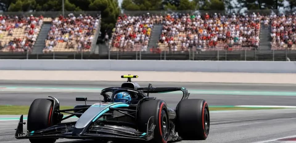 Coche de Fórmula 1 en pista con público al fondo