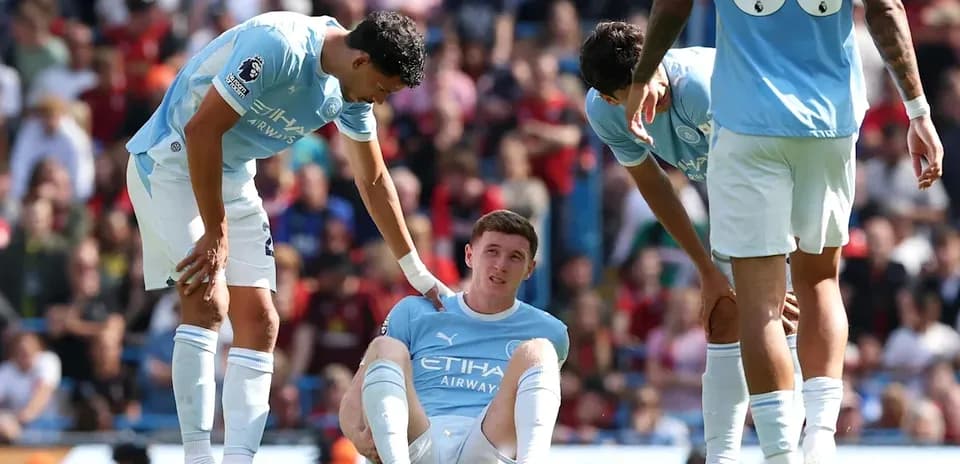 Jugador de Manchester City sentado con compañeros preocupados