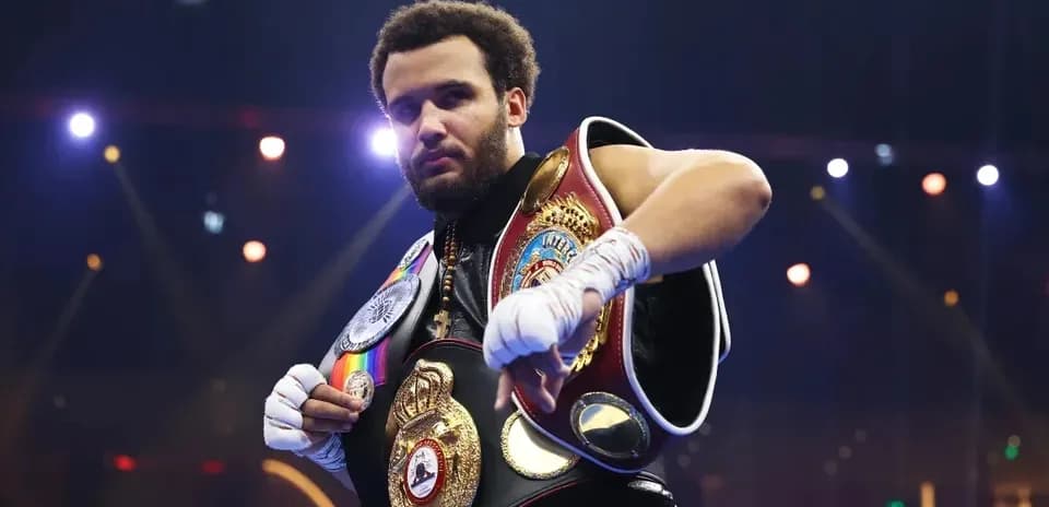 Boxeador mostrando sus cinturones de campeón