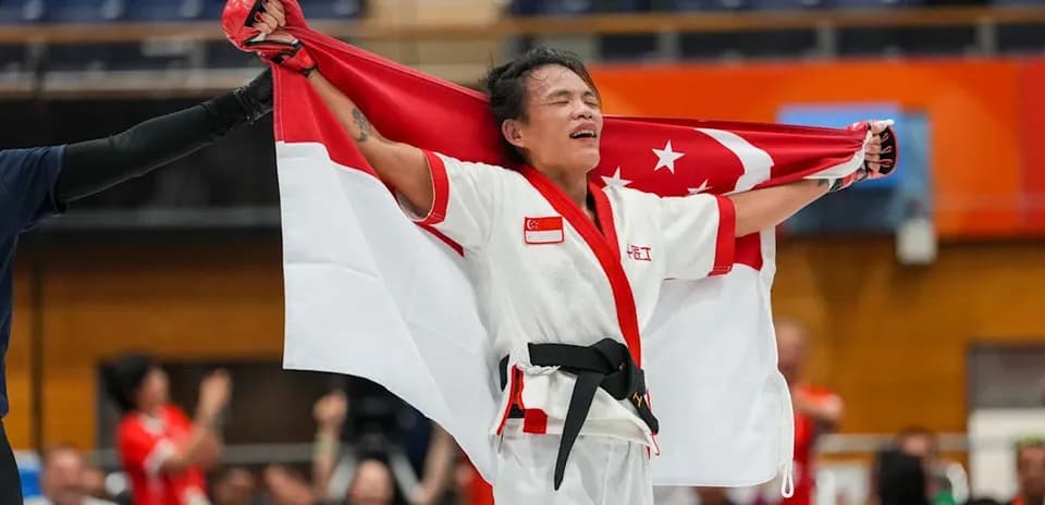 Atleta sosteniendo la bandera de Singapur tras la victoria