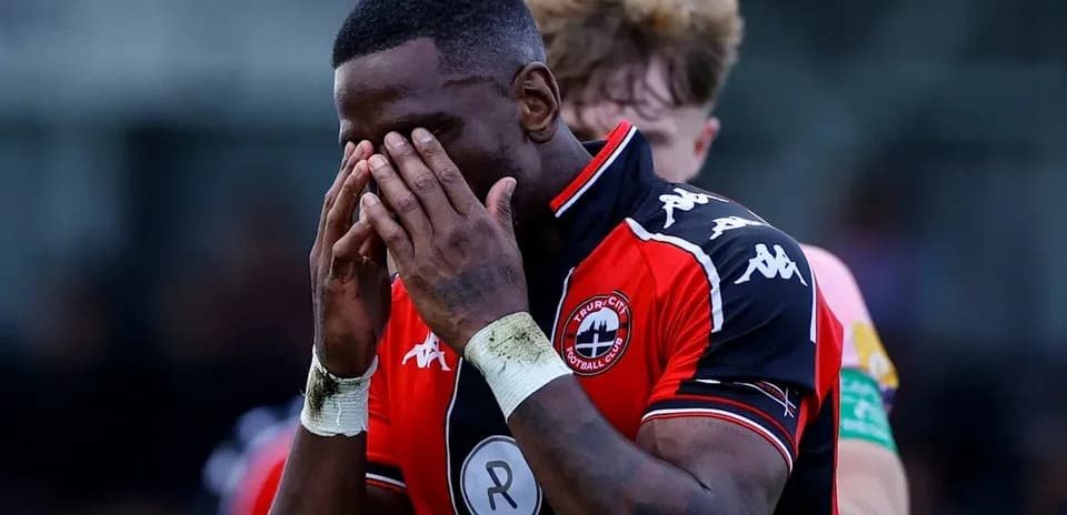 Jugador con camiseta de Truro City cubriéndose la cara