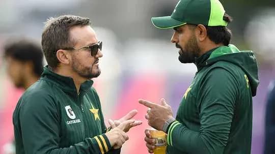 Entrenador y jugador conversando en el campo de cricket