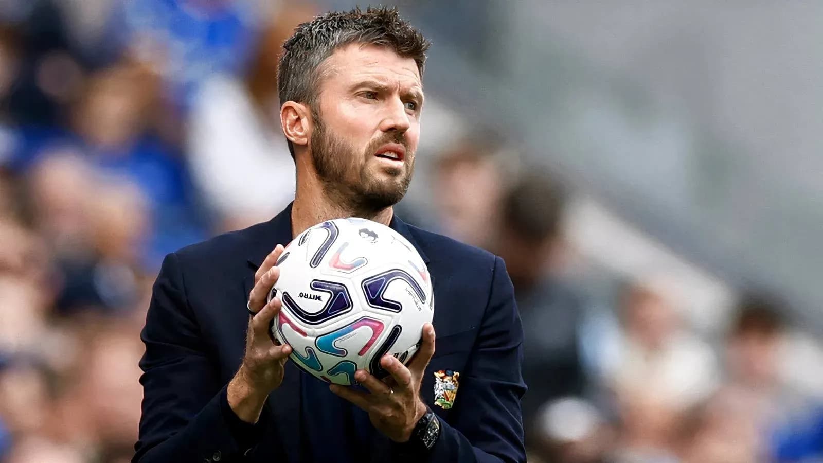 Entrenador sosteniendo un balón de fútbol en el campo
