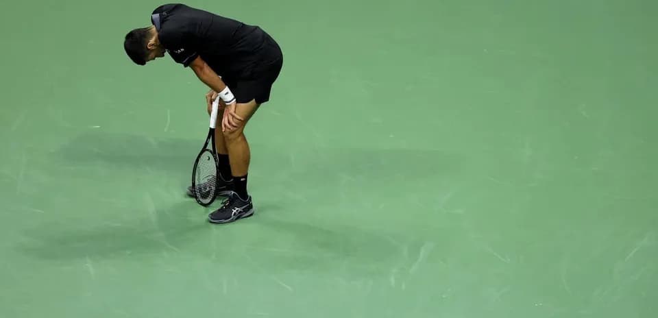 Jugador de tenis agachado sosteniendo su raqueta