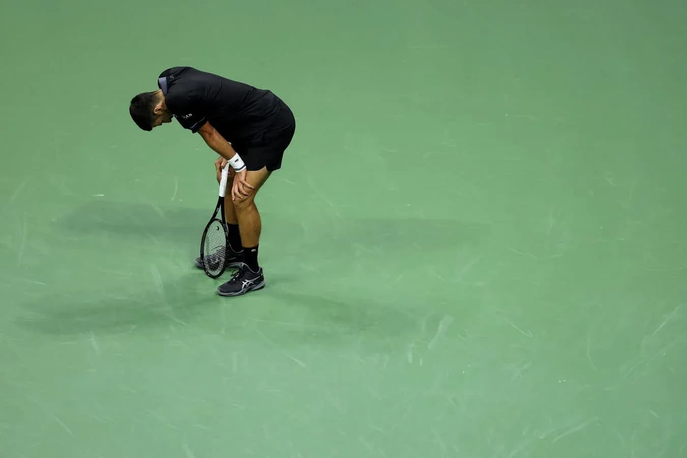 Jugador de tenis agachado sosteniendo su raqueta