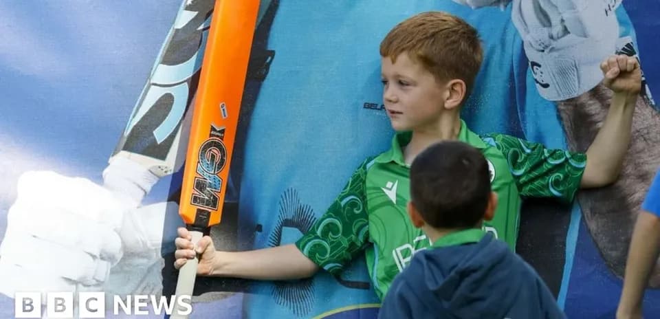Niño sosteniendo un bate de cricket frente a cartel