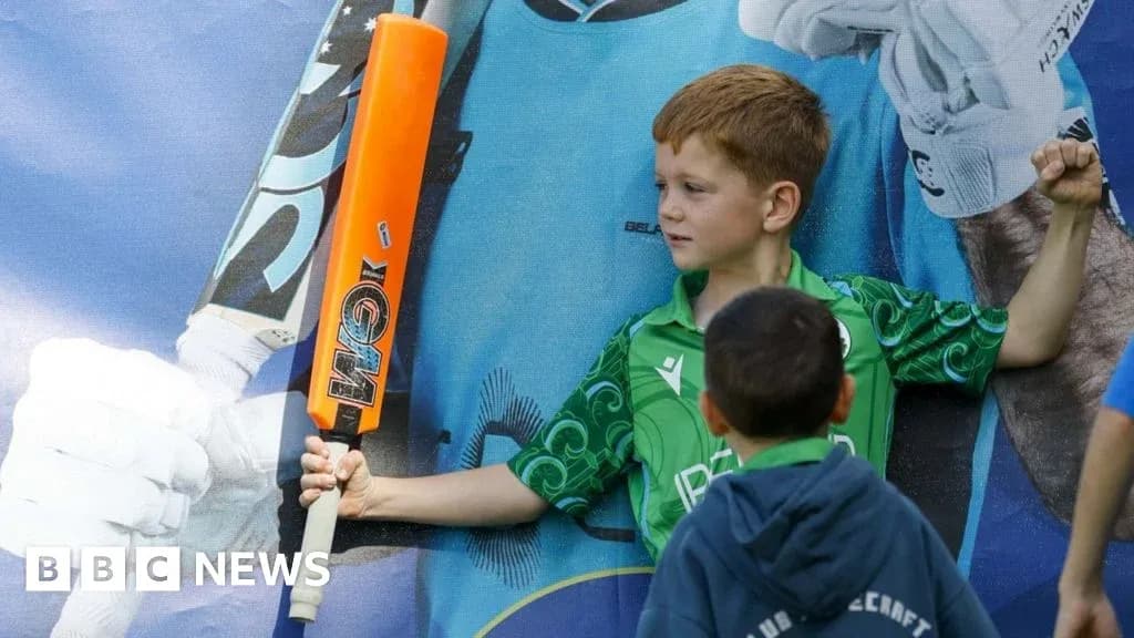 Niño sosteniendo un bate de cricket frente a cartel