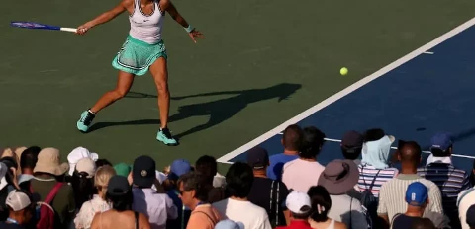 Jugadora de tenis golpeando la pelota frente a la multitud