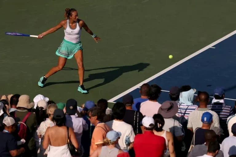 Jugadora de tenis golpeando la pelota frente a la multitud