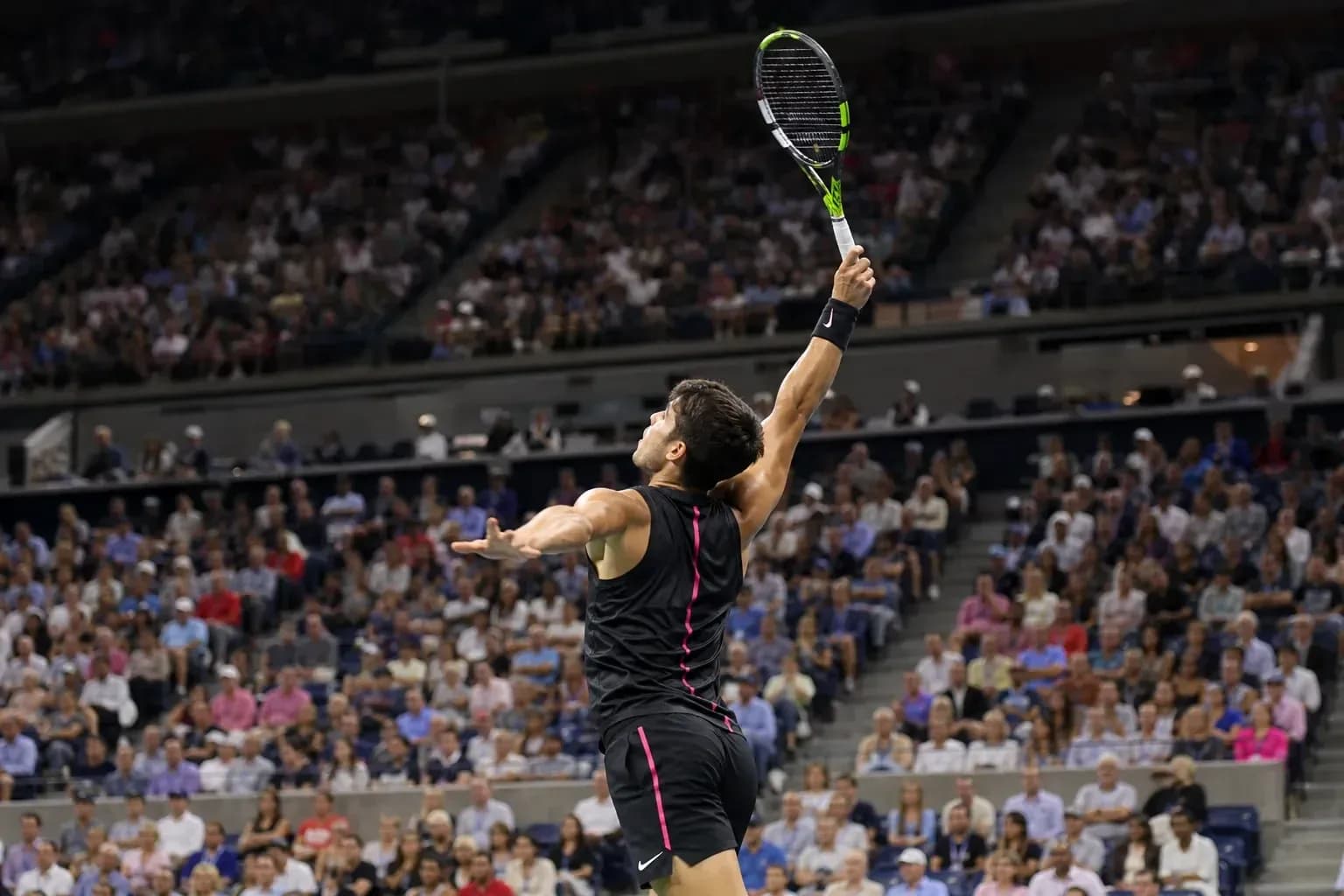 Jugador de tenis sacando en un partido lleno de público