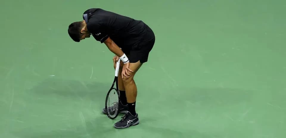 Jugador de tenis doblado sobre la cancha de juego