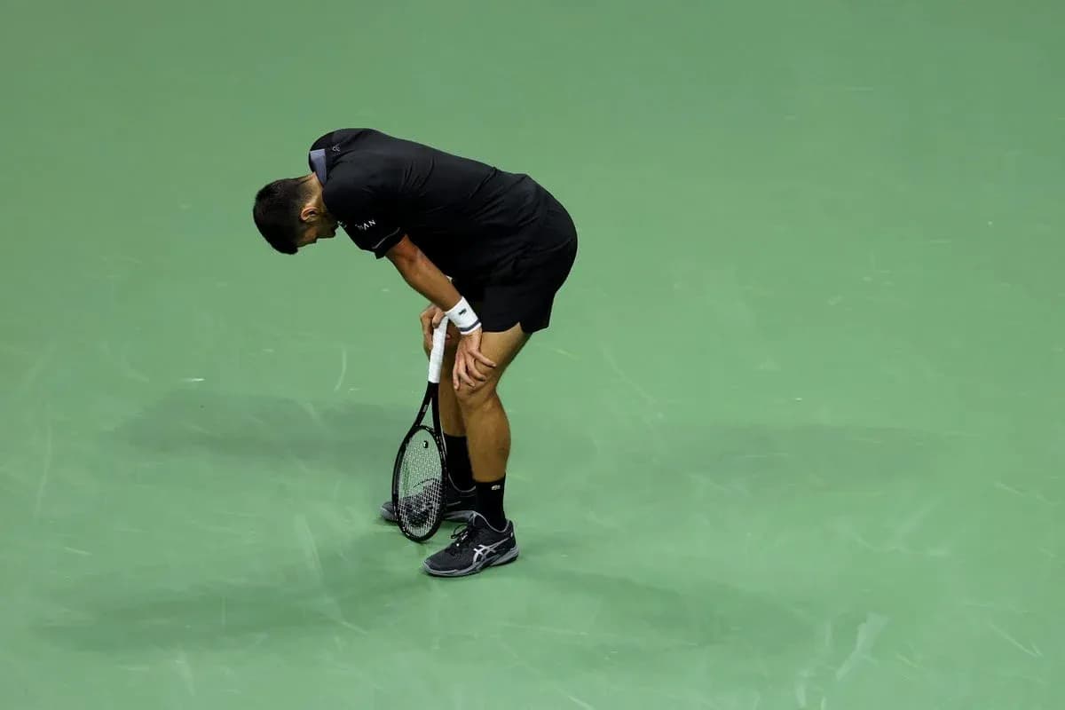 Jugador de tenis doblado sobre la cancha de juego