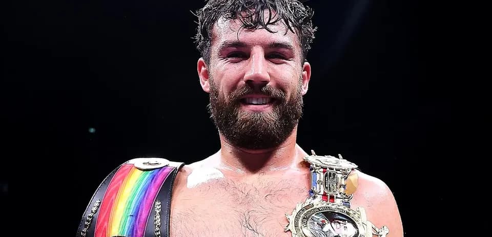 Boxeador sosteniendo cinturones de campeón en el ring