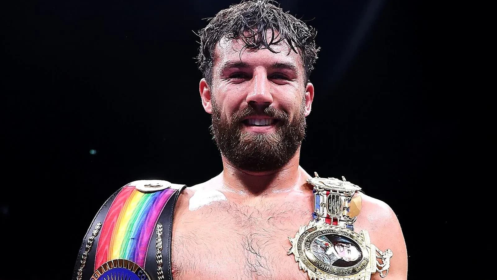 Boxeador sosteniendo cinturones de campeón en el ring