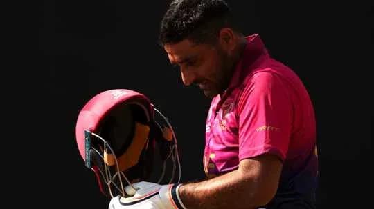 Jugador de cricket ajustando su casco en el campo