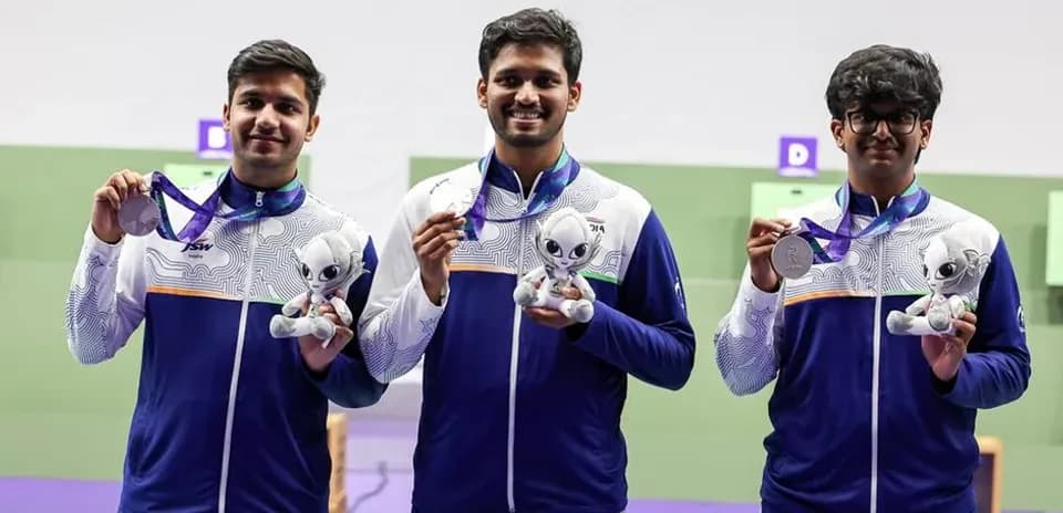 Tres atletas sosteniendo medallas y trofeos en podio