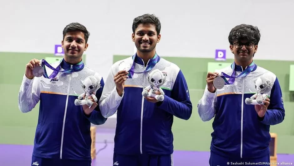 Tres atletas sosteniendo medallas y trofeos en podio