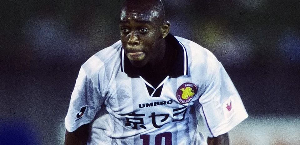 Jugador corriendo en partido de fútbol con camiseta blanca