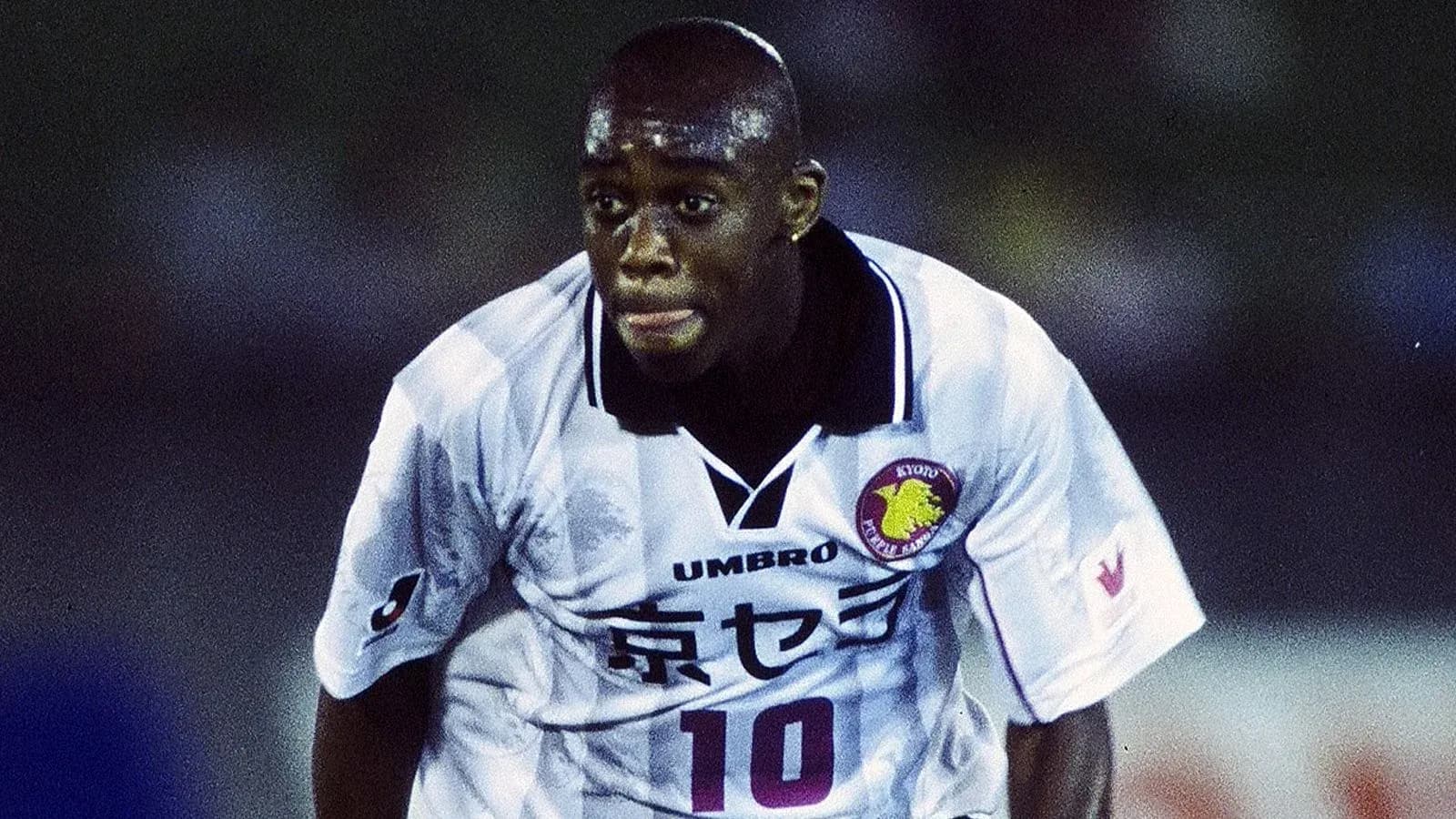 Jugador corriendo en partido de fútbol con camiseta blanca