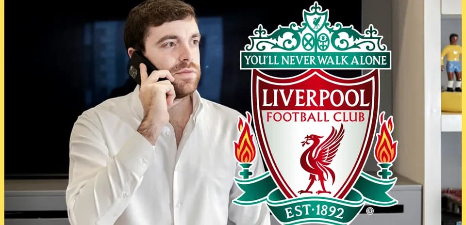 Hombre hablando por teléfono junto al escudo de Liverpool