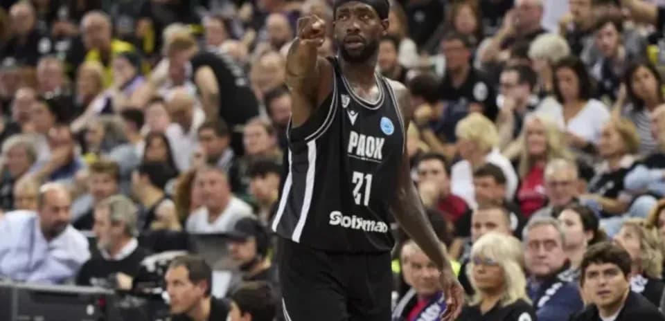 Jugador de baloncesto señalando en partido con afición