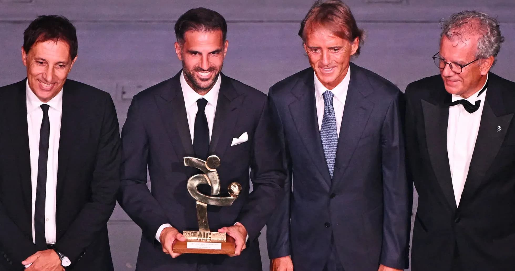 Cuatro hombres posando con un trofeo en evento