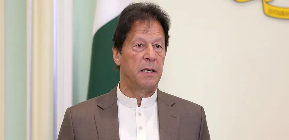 Hombre hablando en un podio con bandera de Pakistán