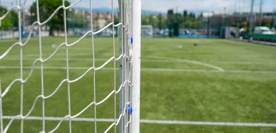 Red de gol en campo de fútbol en día soleado